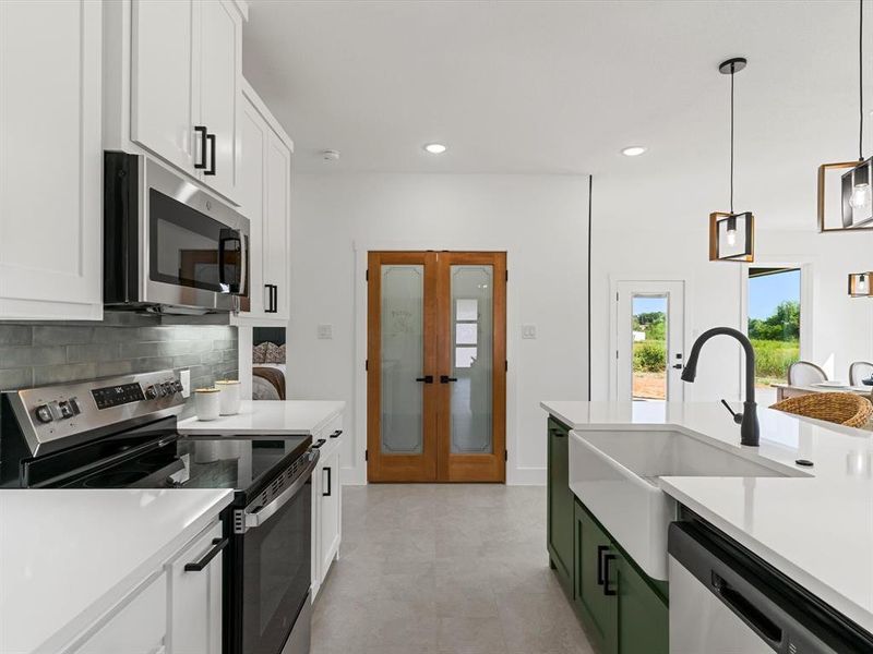 Kitchen with stainless steel appliances, green cabinetry, white cabinetry, pendant lighting, and recessed lighting