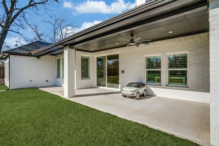 Rear view of house with a lawn, ceiling fan, and a patio area