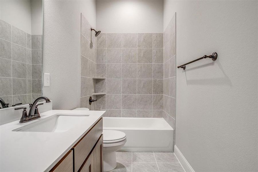 Full bathroom featuring tile patterned flooring, tiled shower / bath combo, toilet, and vanity