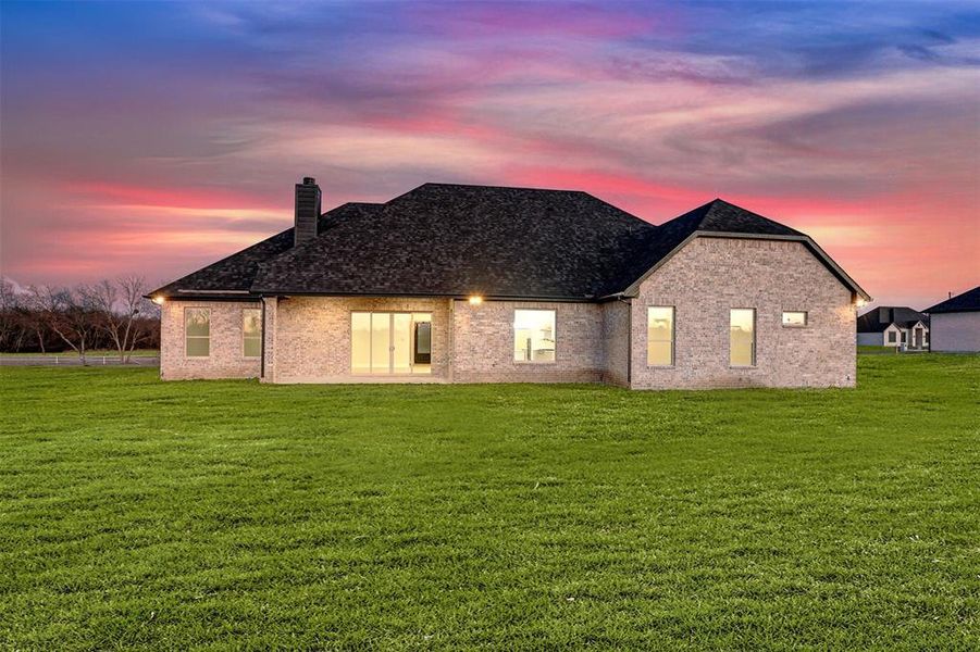 Back house at dusk with a yard