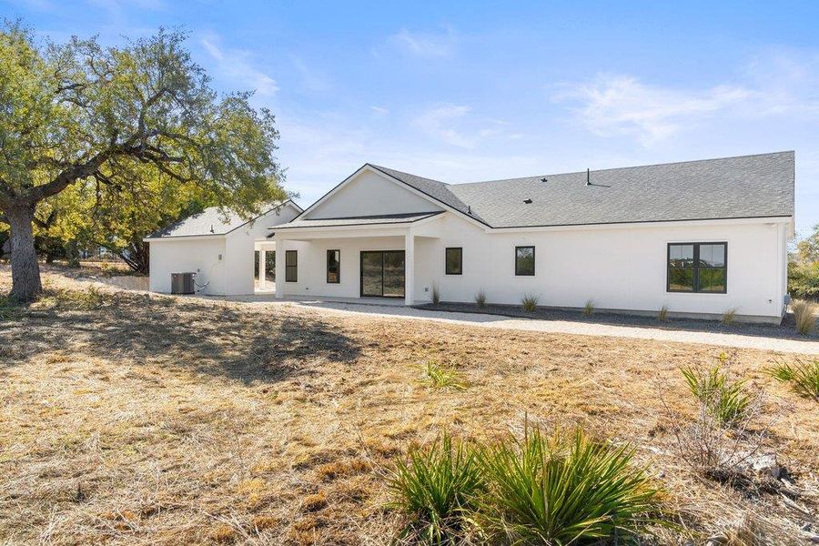 Rear view of property with a patio, stucco siding, and a shingled roof