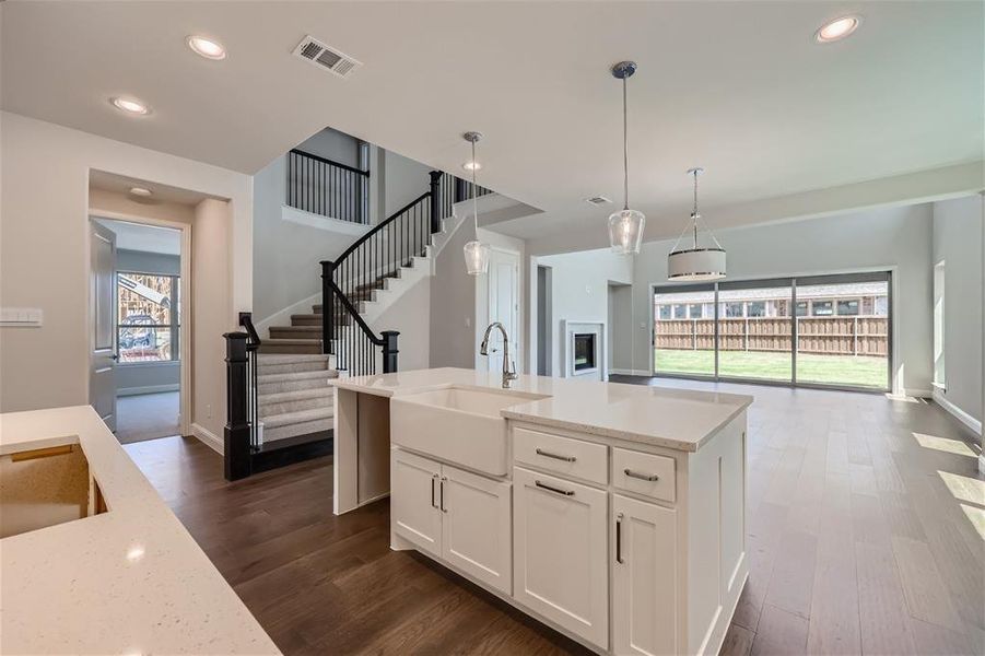 Kitchen featuring a center island with sink, sink, pendant lighting, white cabinetry, and dark hardwood / wood-style flooring