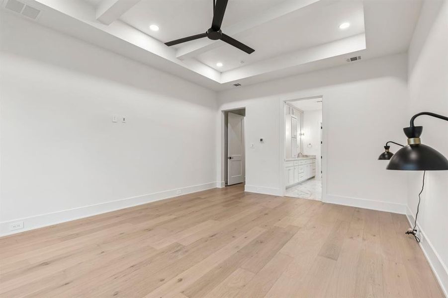 Unfurnished bedroom with light wood-style floors, connected bathroom, ceiling fan, recessed lighting, and beam ceiling