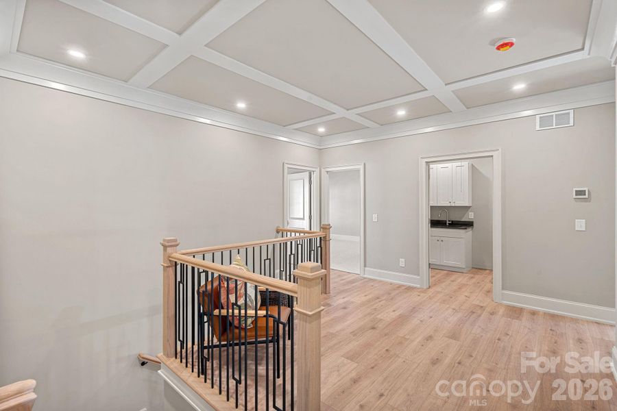 Step upstairs to a second-floor landing with a sitting area under a gorgeous coffered ceiling—an inviting spot for relaxation or quiet moments.