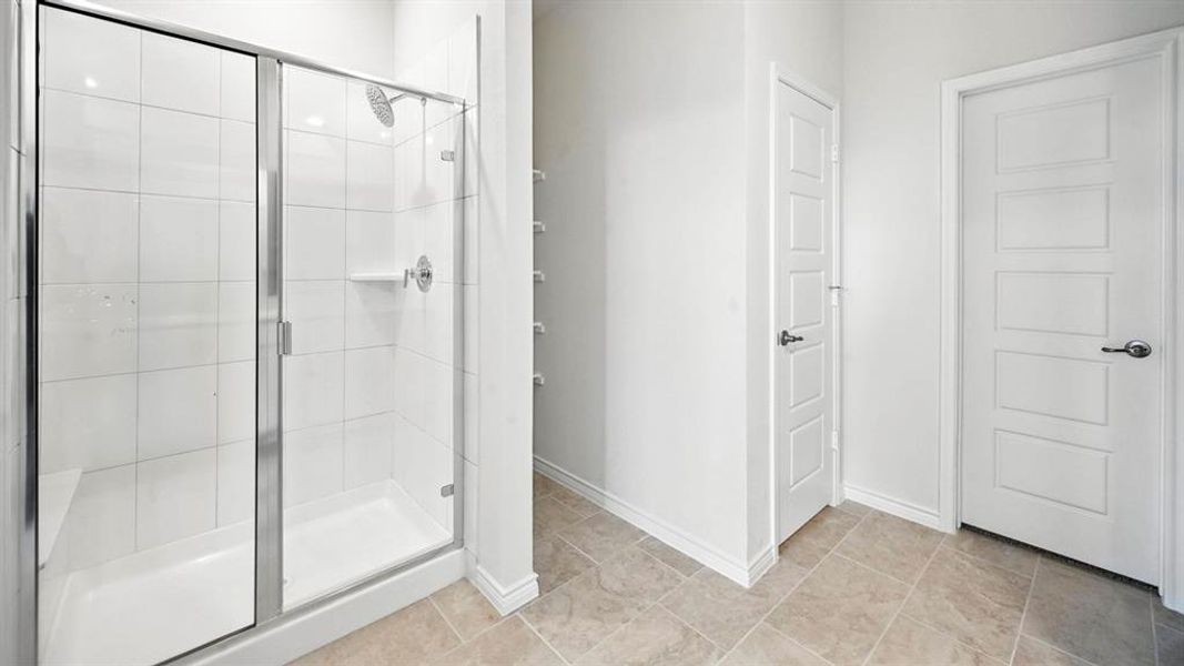 Glass-enclosed shower with white tiled walls and integrated shelving