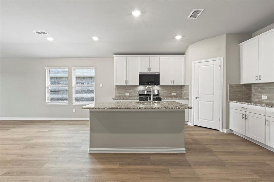 Kitchen with appliances with stainless steel finishes, decorative backsplash, recessed lighting, light stone countertops, and light wood-style flooring Kitchen with appliances with stainless steel finishes, decorative backsplash, recessed lighting, light stone countertops, and light wood-style flooring