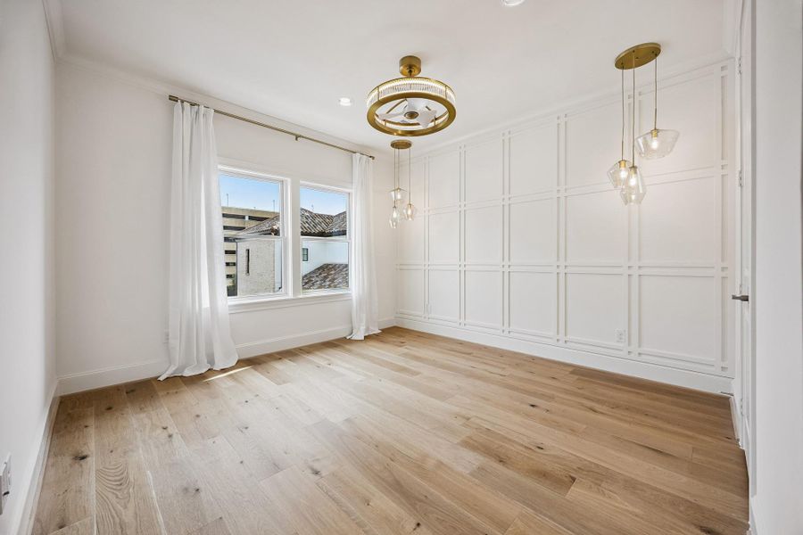 Down the hall from the primary, this secondary bedroom has hardwood floors, custom wall detail and designer lighting.