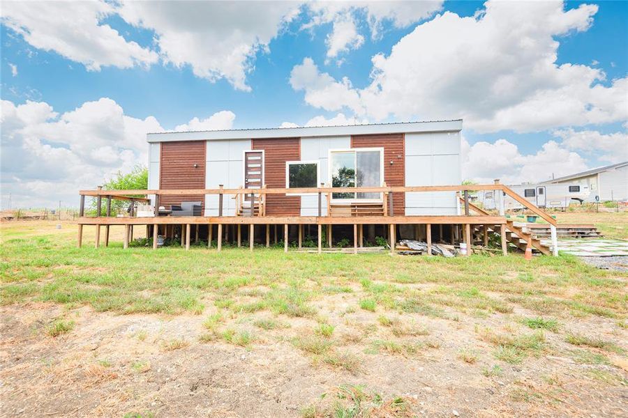 Back of house featuring a wooden deck and a metal roof Back of house featuring a wooden deck and a metal roof