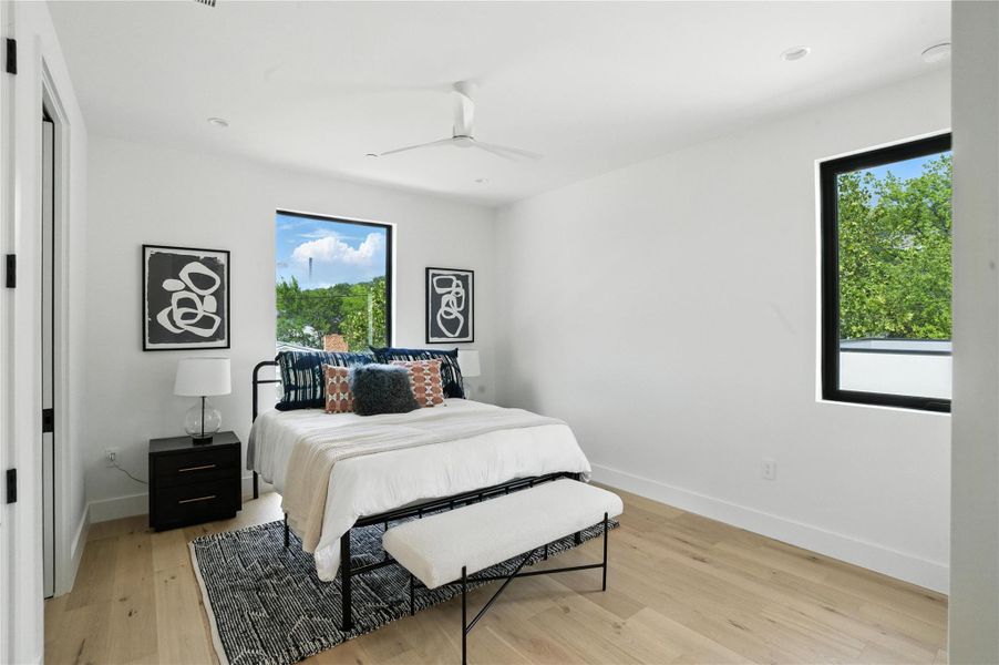 Bedroom with multiple windows, light wood-style flooring, and ceiling fan Bedroom with multiple windows, light wood-style flooring, and ceiling fan