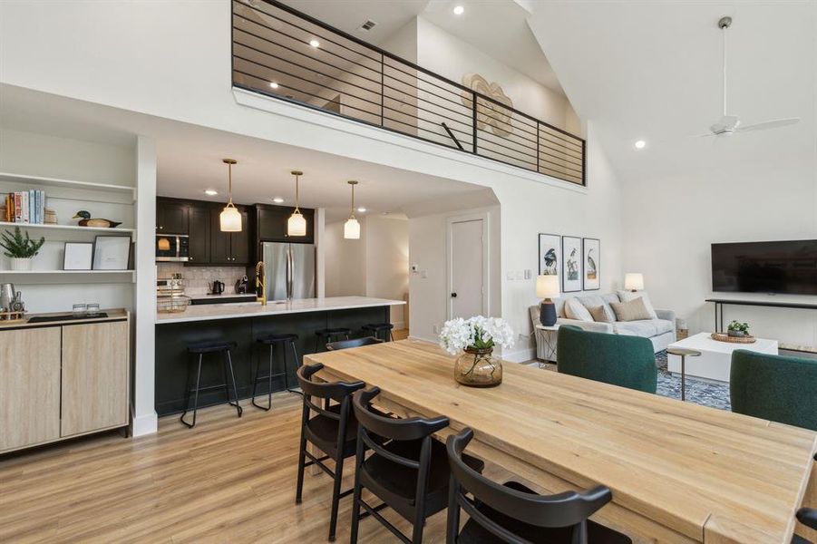 Dining area with high vaulted ceiling, light wood-type flooring, and ceiling fan
