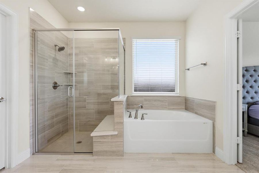 Contemporary master bathroom featuring a large soaking tub with chrome fixtures, a spacious walk-in shower with a glass enclosure and built-in bench, and light-toned tile flooring