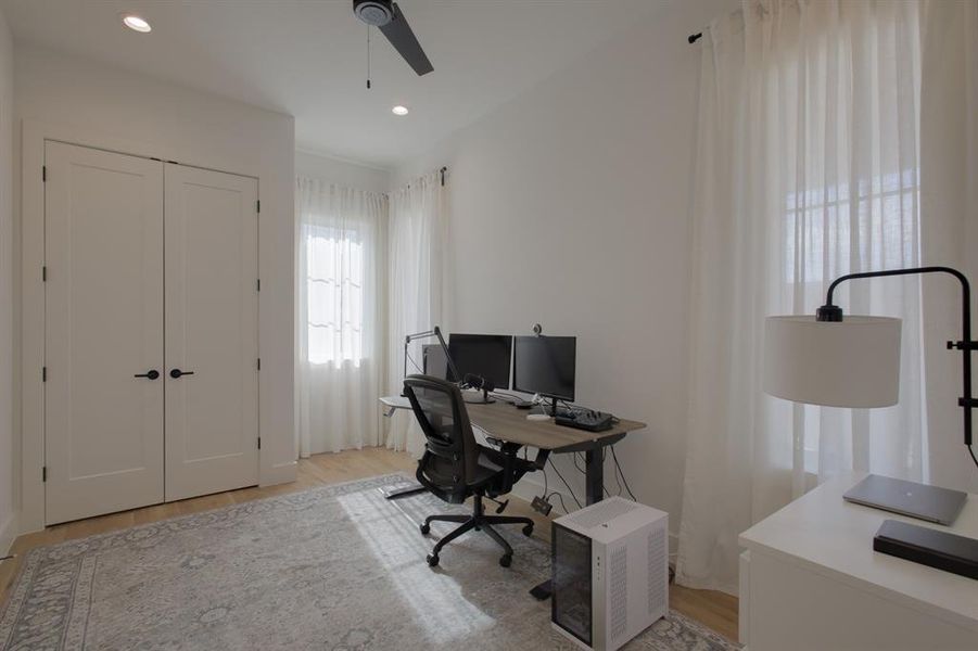 Office with light wood-type flooring and ceiling fan