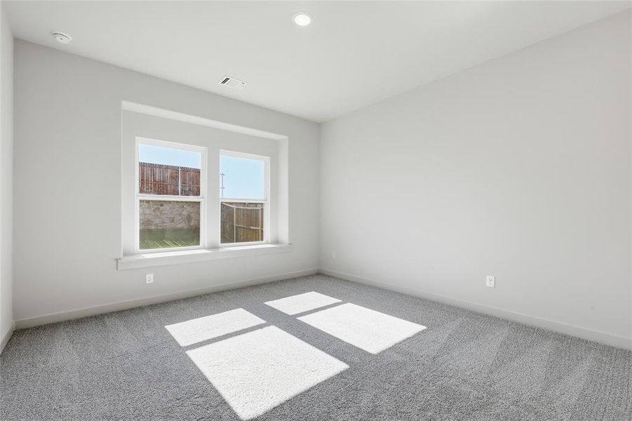 Bright interior room featuring a recessed window, plush gray carpet, and crisp white walls
