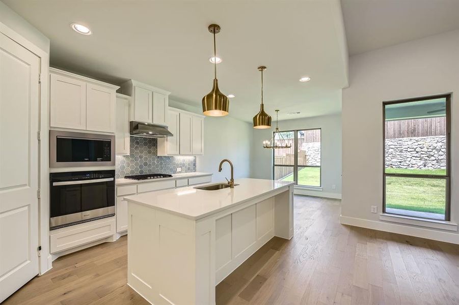 Kitchen with stainless steel appliances, white cabinetry, decorative backsplash, light countertops, and recessed lighting Kitchen with stainless steel appliances, white cabinetry, decorative backsplash, light countertops, and recessed lighting