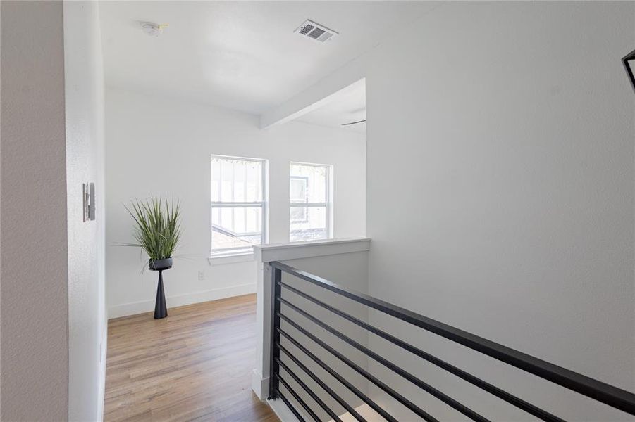 Hallway with an upstairs landing, light wood finished floors, and beam ceiling Hallway with an upstairs landing, light wood finished floors, and beam ceiling