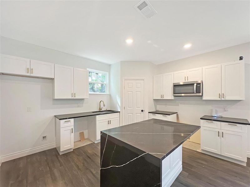 Kitchen featuring stainless steel microwave, dark wood-style flooring, white cabinetry, dark countertops, and recessed lighting Kitchen featuring stainless steel microwave, dark wood-style flooring, white cabinetry, dark countertops, and recessed lighting