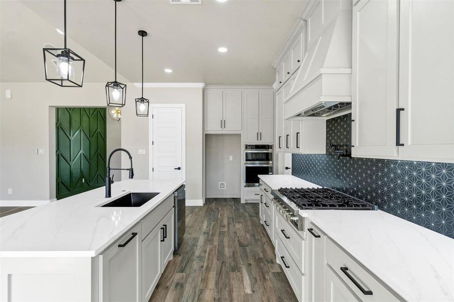 Kitchen with white cabinetry, an island with sink, sink, and custom range hood