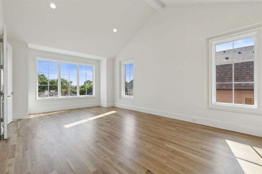 Primary bedroom with light wood-type flooring, beam ceiling, and high vaulted ceiling