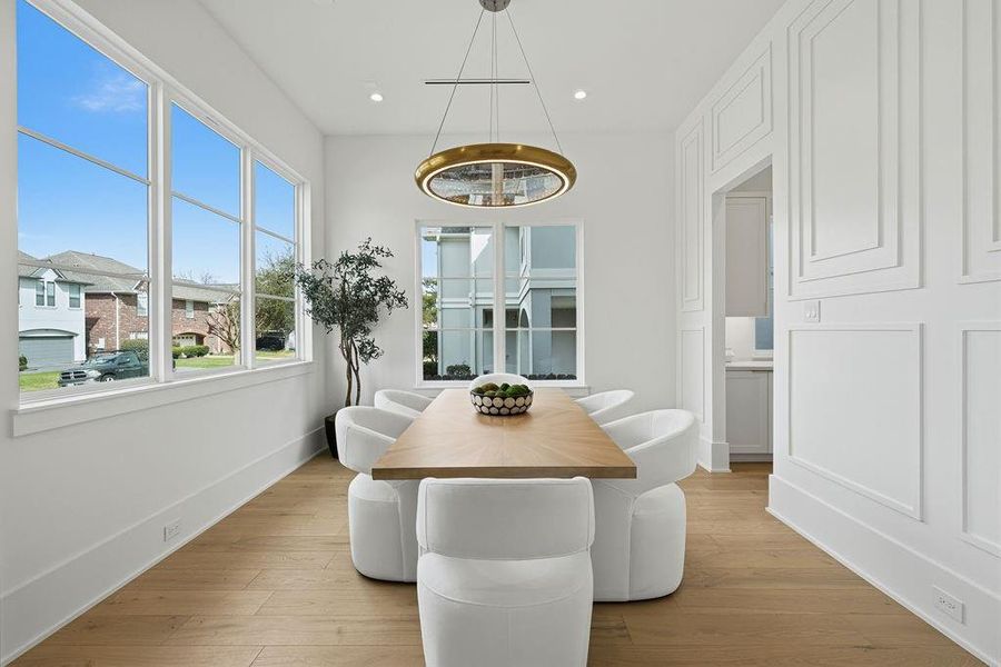 A bright, contemporary dining space ideal for hosting dinners and gatherings, with large windows, modern lighting, and elegant architectural details