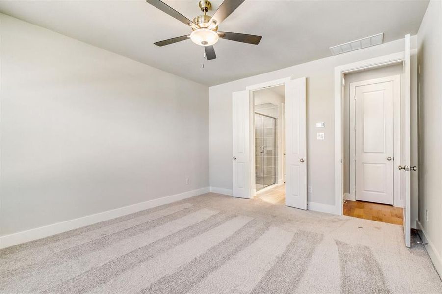 Unfurnished bedroom featuring light carpet, connected bathroom, and a ceiling fan