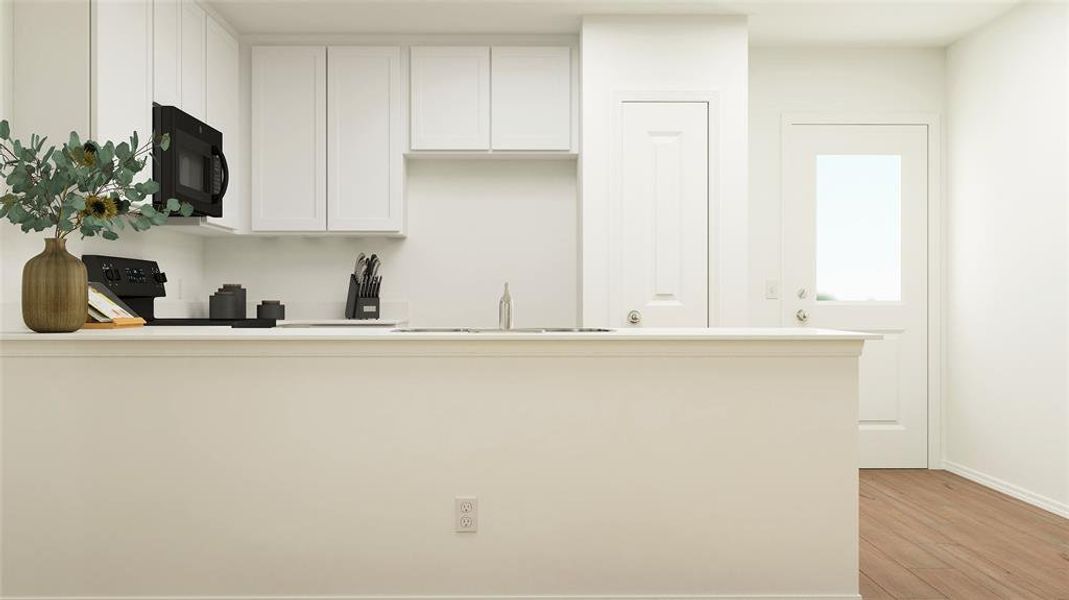 Kitchen with white cabinetry, sink, kitchen peninsula, stove, and light wood-type flooring