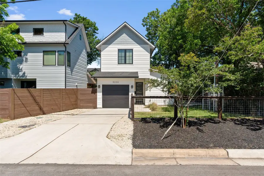 Modern two-story residence featuring white siding, a single-car garage, and dark-framed windows. Fully fenced front yard. Modern two-story residence featuring white siding, a single-car garage, and dark-framed windows. Fully fenced front yard.