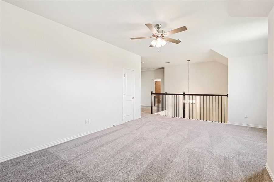 Empty room featuring carpet, ceiling fan, and vaulted ceiling