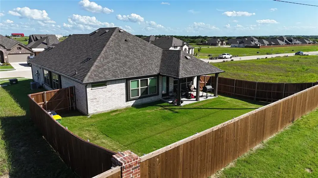 Expansive backyard featuring a full perimeter wood privacy fence with brick pillars, a covered patio area, and a rectangular lawn space Expansive backyard featuring a full perimeter wood privacy fence with brick pillars, a covered patio area, and a rectangular lawn space