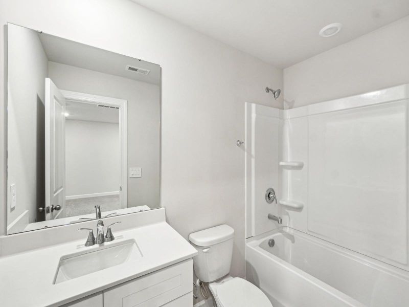 The secondary bathroom features an oversized tub and large mirror.