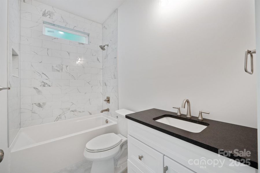 Hall bathroom with tub to ceiling tile, leathered granite—- this home compares to none