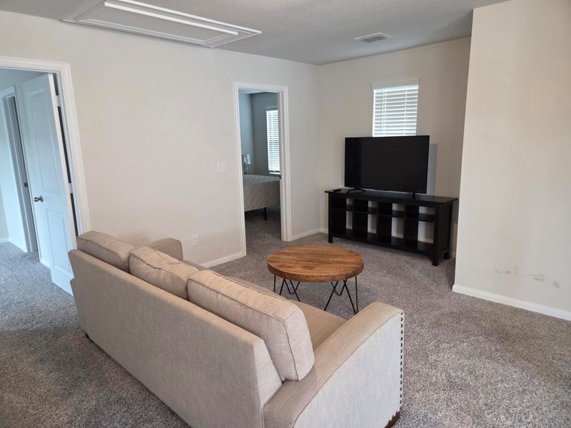 Carpeted living space featuring recessed lighting and a window with blinds