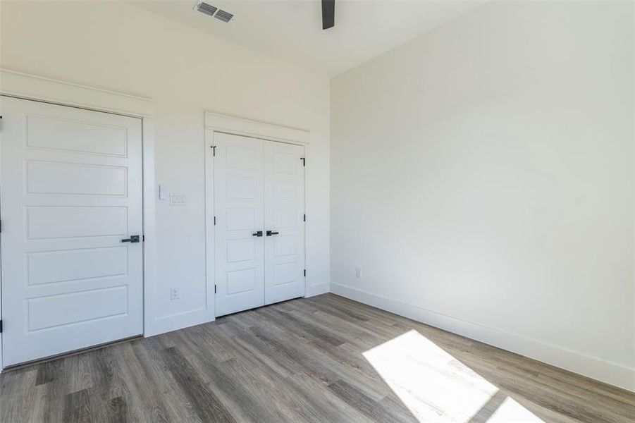 Unfurnished bedroom featuring wood-type flooring, ceiling fan, and a closet