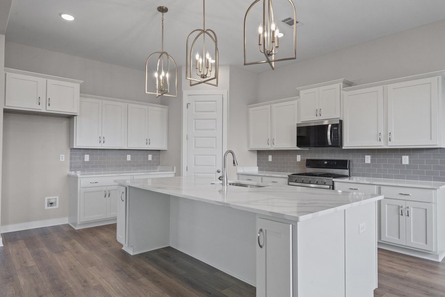 Kitchen with white cabinets, pendant lighting, light stone countertops, appliances with stainless steel finishes, and recessed lighting