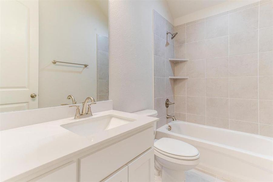 Full bathroom featuring vanity, tiled shower / bath, and toilet