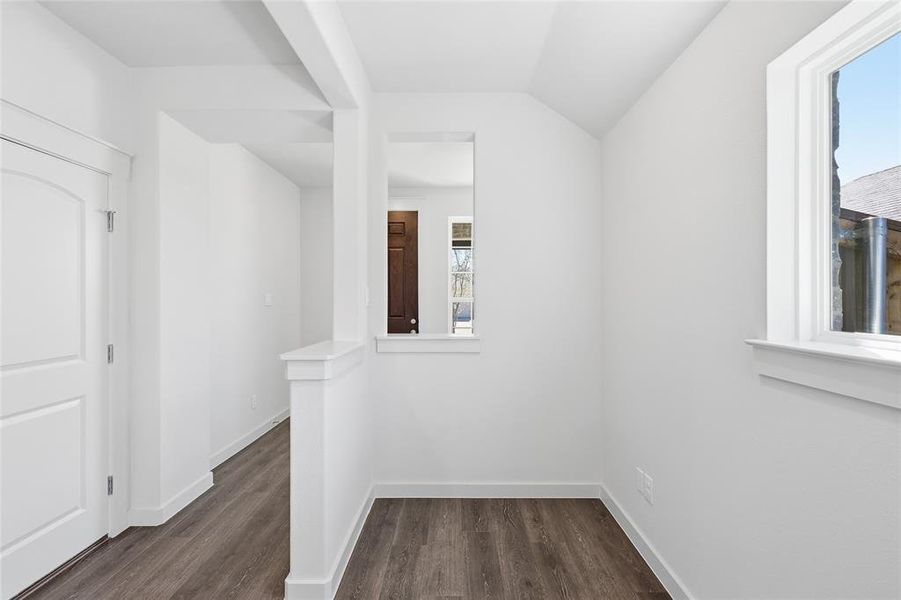 Hall with dark wood finished floors and vaulted ceiling
