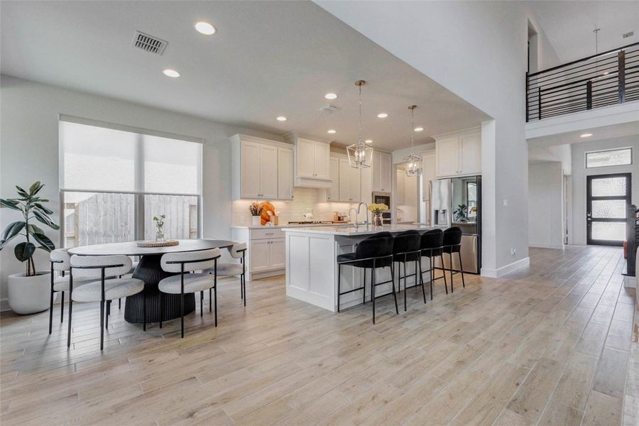 This modern, open-concept kitchen features sleek white cabinets, a large island with seating, stainless steel appliances, and abundant natural light. The space seamlessly connects to a dining area and living space, creating an inviting atmosphere for entertaining. This modern, open-concept kitchen features sleek white cabinets, a large island with seating, stainless steel appliances, and abundant natural light. The space seamlessly connects to a dining area and living space, creating an inviting atmosphere for entertaining.
