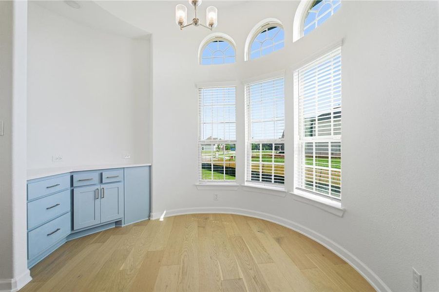 Curved bay window area featuring light wood-finish flooring and integrated cabinetry with a light blue finish and white countertop
