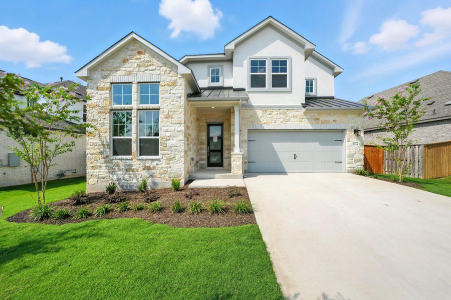 View of front facade featuring a standing seam roof, stone siding, a metal roof, an attached garage, and concrete driveway View of front facade featuring a standing seam roof, stone siding, a metal roof, an attached garage, and concrete driveway
