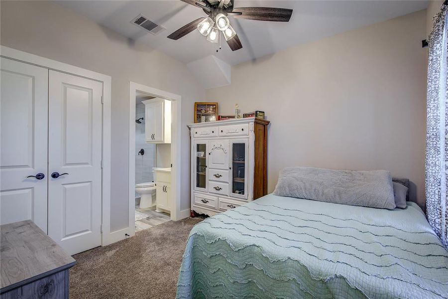 Carpeted bedroom with ceiling fan, ensuite bathroom, and a closet