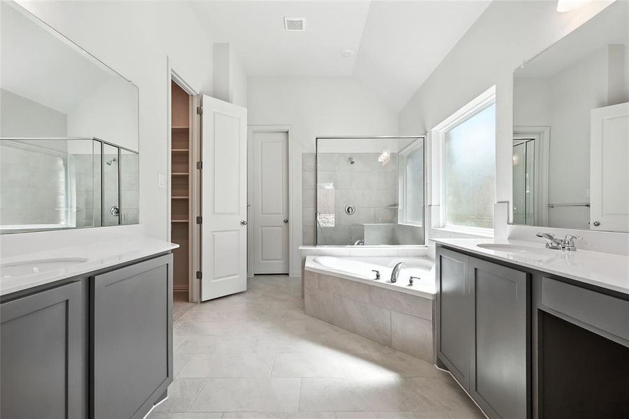 Full bath with two vanities, lofted ceiling, a shower stall, a garden tub, and a walk in closet Full bath with two vanities, lofted ceiling, a shower stall, a garden tub, and a walk in closet