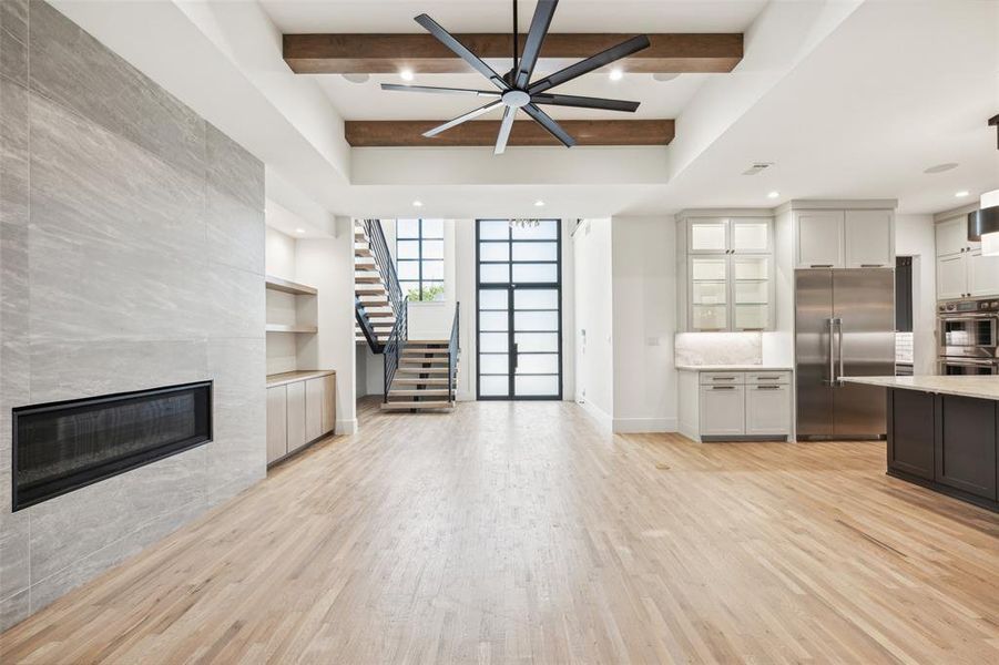 Kitchen with light hardwood / wood-style floors, beam ceiling, a tile fireplace, and stainless steel appliances