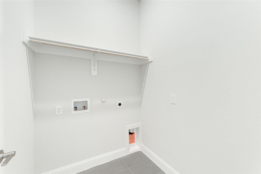 Laundry room with white walls, upper shelf, washer hookups, gas connection, and tile floor Laundry room with white walls, upper shelf, washer hookups, gas connection, and tile floor