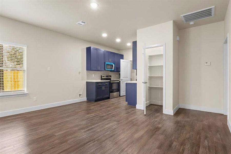 Kitchen featuring dark wood-type flooring, blue cabinets, decorative backsplash, and electric range