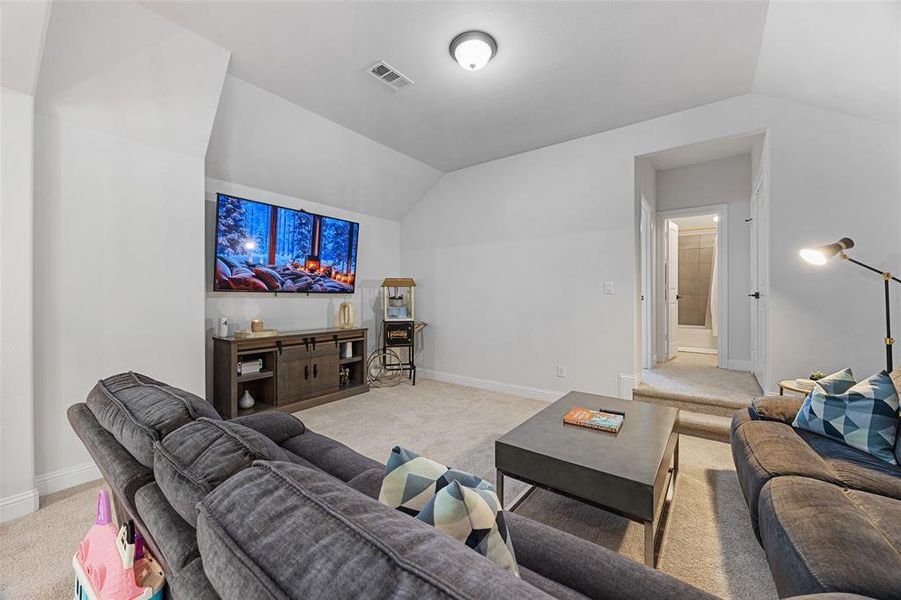 Living room with light colored carpet, baseboards, visible vents, and vaulted ceiling