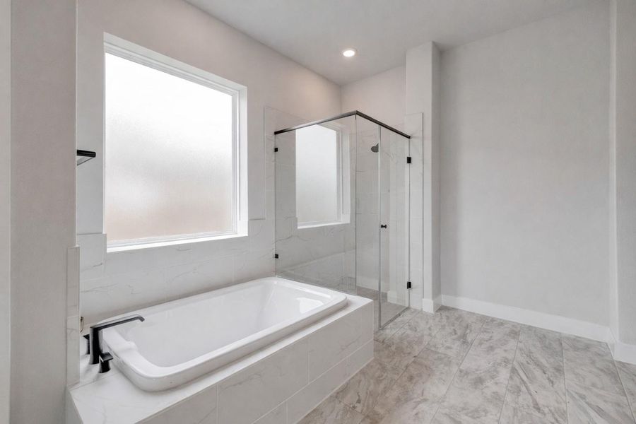 Bathroom with a built-in bathtub, a window, and a glass-enclosed shower