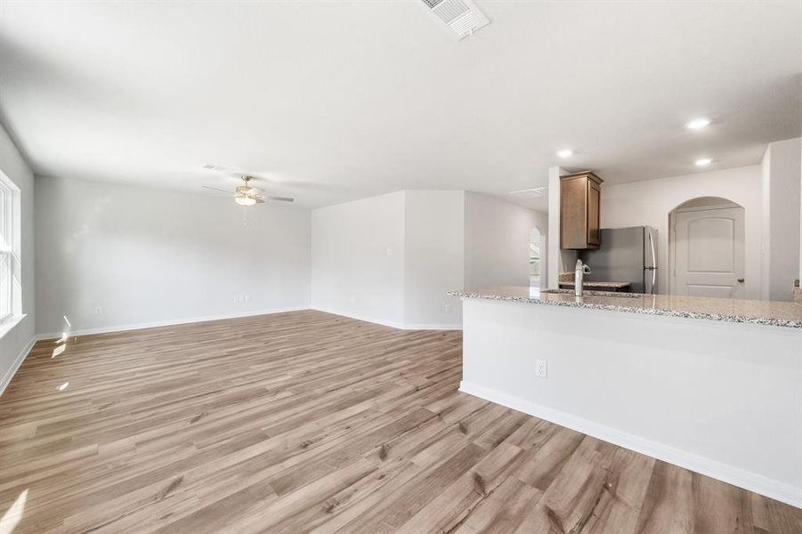 Unfurnished living room featuring ceiling fan and light hardwood / wood-style floors