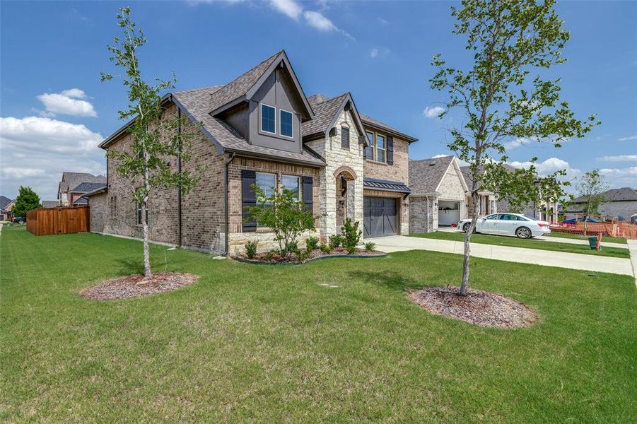 View of front facade with driveway, an attached garage, brick siding, and stone siding