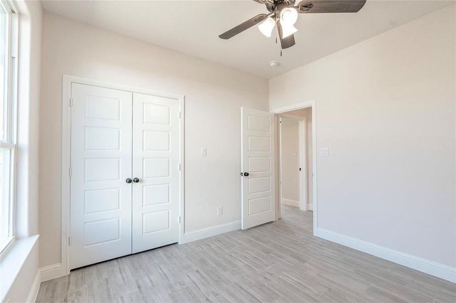 Unfurnished bedroom with ceiling fan, a closet, and light hardwood / wood-style floors