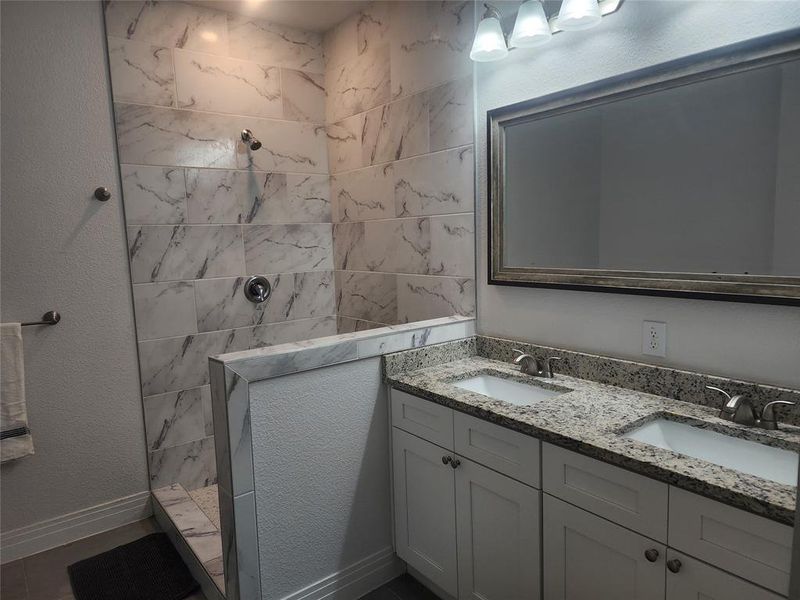 Bathroom featuring vanity and a tile shower