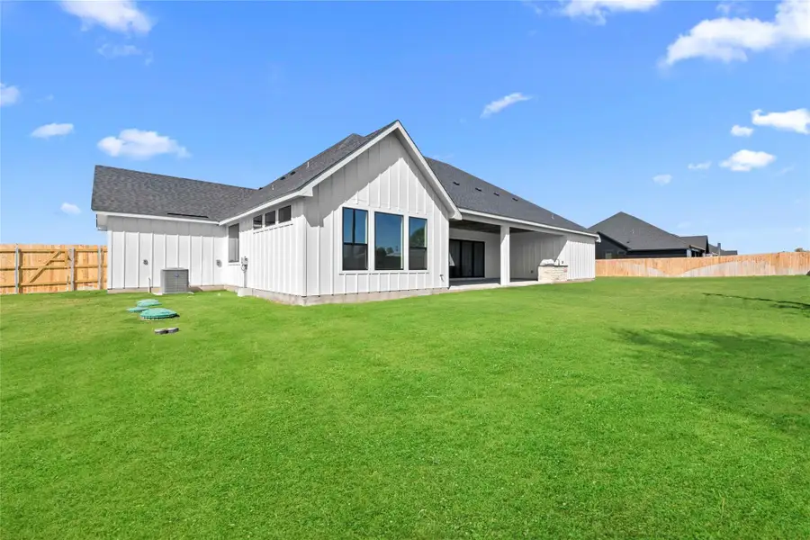 Rear view of house featuring a shingled roof, board and batten siding, a fenced backyard, and a patio area Rear view of house featuring a shingled roof, board and batten siding, a fenced backyard, and a patio area